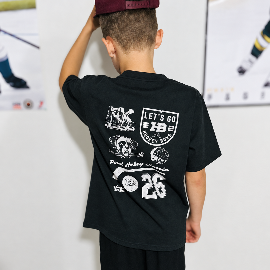 Youth model wearing the Charcoal Youth Hockey T-Shirt, back view, with hockey posters in the background